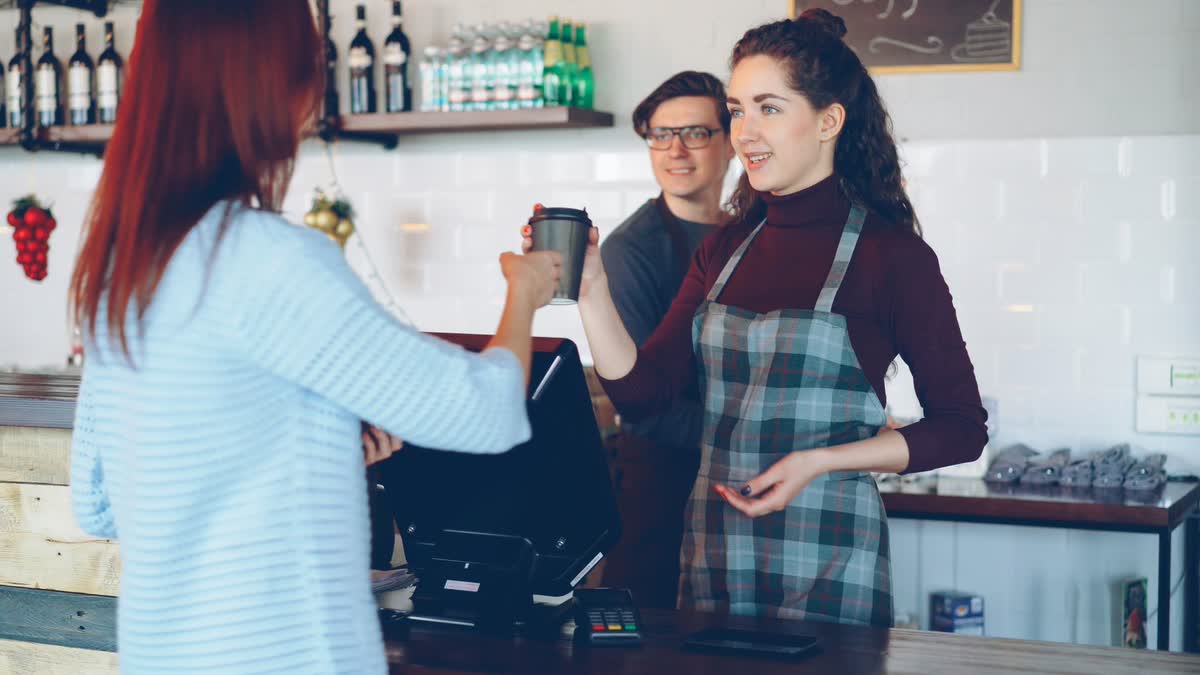 A barista handing a drink across the counter